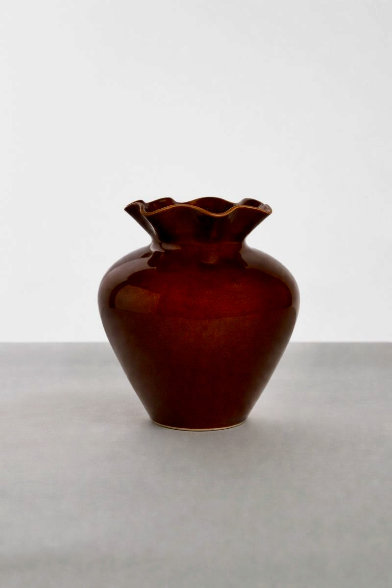 Brown ceramic vase with a wavy mouthpiece on a white background